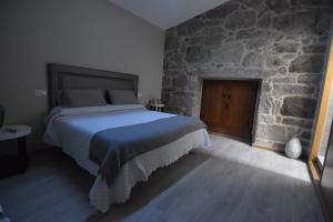 sypialnia z łóżkiem i kamienną ścianą w obiekcie Casa A Pedra w mieście Morgadanes