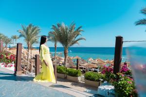 a woman in a yellow dress walking on the beach at Sunrise Montemare Resort -Grand Select in Sharm El Sheikh