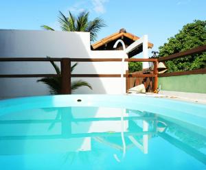 a blue swimming pool with a white fence at Pousada Vila Mundi Itaúnas in Itaúnas