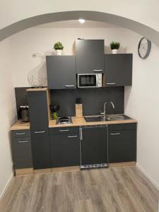 a kitchen with black cabinets and a microwave at Prime Host Lovely Apartment in Karlsruhe
