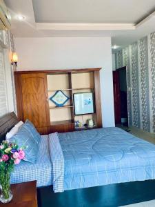 a bedroom with a blue bed and a vase of flowers at Lucys Hotel in Vung Tau
