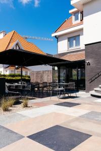 a patio with tables and chairs under an umbrella at ENSO - Boutique Hotel in Knokke-Heist