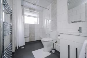 La salle de bains blanche est pourvue de toilettes et d'un lavabo. dans l'établissement Cherry Tree Cottage, à Thornton