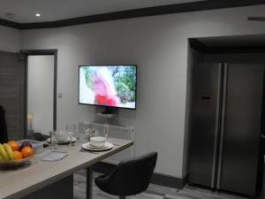 a living room with a table and a tv on the wall at Townhouse PLUS @ 282 Walthall Street in Crewe