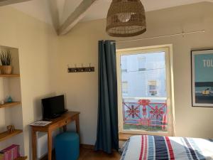 um quarto com uma janela, uma cama e uma televisão em Le pigeonnier de la plume em Nantes