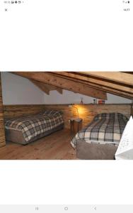 Duas camas num quarto com pisos em madeira em Mansarda la Baita em Madonna di Campiglio