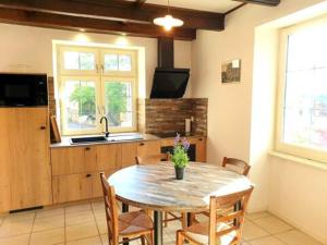 a kitchen with a wooden table with chairs and a sink at Chez Tata Célestine in Castelnau-Pégayrols