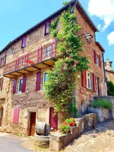 a stone building with flowers on the side of it at Chez Tata Célestine in Castelnau-Pégayrols
