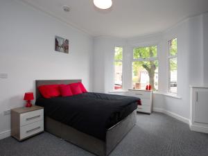 a bedroom with a bed with red pillows and windows at Townhouse @ 97 Ruskin Road Crewe in Crewe