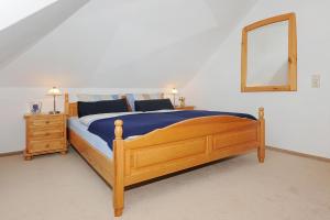 a bedroom with a wooden bed and a mirror at Ferienwohnung im Haus Solea in Esens