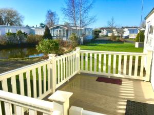 a wooden deck with a white fence and a house at Beautiful 3 bed caravan SouthviewPark Skegness in Skegness