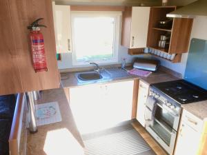 a small kitchen with a stove and a sink at Beautiful 3 bed caravan SouthviewPark Skegness in Skegness