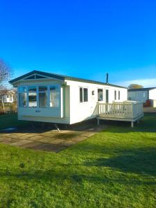 a small white house with a porch on a lawn at Beautiful 3 bed caravan SouthviewPark Skegness in Skegness