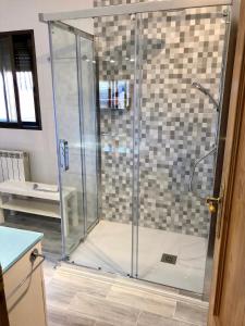 a shower with a glass door in a bathroom at Casa en el corazón de Gredos, amplia y agradable. in Navacepeda de Tormes