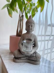 Une statue assise sur une table à côté d'une plante dans l'établissement Isenbüttel Ferienwohnung, à Isenbüttel