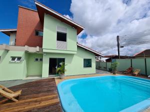 une villa avec une piscine en face d'une maison dans l'établissement Vila Itanhaém, à Itanhaém