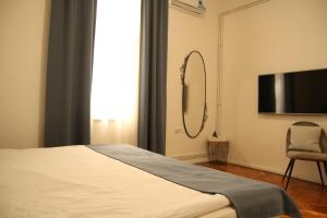 Schlafzimmer mit einem Bett, einem TV und einem Stuhl in der Unterkunft Natalie's Royal M in Belgrad