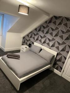 a bedroom with a white bed with a geometric wall at Coast View Apartments in Whitley Bay
