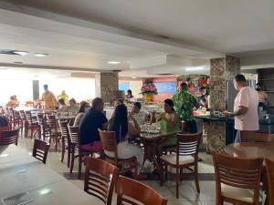 a group of people sitting at tables in a restaurant at Beira Mar Imperial Flat 612 in João Pessoa