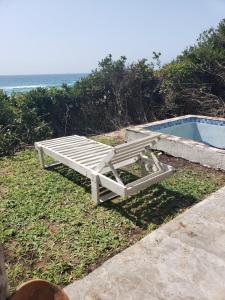 a wooden bench next to a swimming pool at Complexo Baleia Azul Camping in Ponta do Ouro