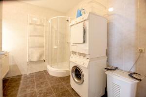 a washing machine in a bathroom with a shower at Kustverhuur, Prachtig appartement met uitzicht op zee, Port Scaldis 09-051 in Breskens