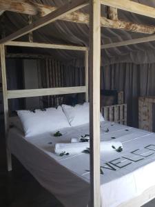 ein großes Bett mit weißer Bettwäsche und Kissen darauf in der Unterkunft Complexo Baleia Azul Camping in Ponta do Ouro
