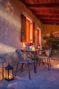 a patio with a table and chairs and a lantern at Pink house in Drepana