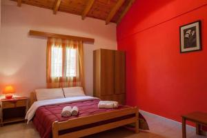 a bedroom with a bed with a red wall at Pink house in Drepana