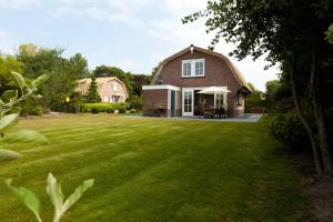 a house with a thatched roof and a yard at Het Eerste Huisje vacation home in Noordwijk aan Zee +8 photos