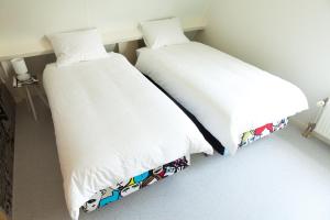 two beds in a room with white sheets at Het Eerste Huisje vacation home in Noordwijk aan Zee