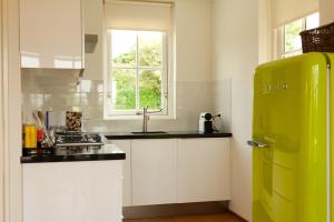 ノールトウェイク・アーン・ゼーにあるHet Eerste Huisje vacation homeのキッチン(白いキャビネット、緑の冷蔵庫付)