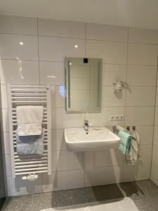 ein Badezimmer mit einem Waschbecken, einem Spiegel und Handtüchern in der Unterkunft Privatzimmer Hoffmann in Kaltenborn