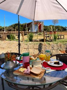 a glass table with a tray of food and drinks at Ecaffe Hotel Pousada Container - Coqueiral MG in Coqueiral