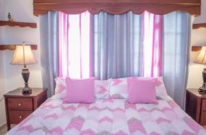 a bedroom with a bed with a pink and white comforter at Penthouse con jacuzzi La cueva de los 3 ojos in Santo Domingo