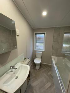 Un baño con inodoro, lavabo y ducha. en Darwin Lodge with Hot Tub, en Malton