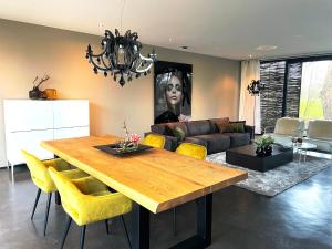 uma sala de estar com uma mesa de madeira e cadeiras amarelas em Betonnen Boshuis em Oosterhout