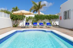 a swimming pool with chairs and an umbrella at Villa hermosa in Puerto del Carmen