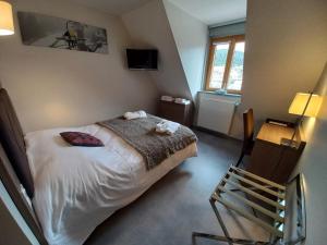 a bedroom with a bed and a chair in it at Hôtel *** Les Tremplins in La Chaux Neuve