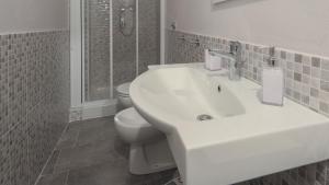 a white bathroom with a sink and a toilet at Welcomely - Residenza Deriu in Bosa