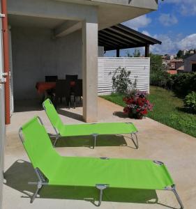 un par de sillas verdes sentadas en un patio en Apartments Mali Losinj (72) en Mali Lošinj