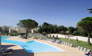 een zwembad met stoelen en mensen die er omheen staan bij Belambra Clubs Résidence Gruissan - Les Ayguades in Gruissan