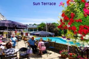 a group of people sitting at tables near a swimming pool at Templestowe Hotel, Number One for Entertainment in Torquay in Torquay