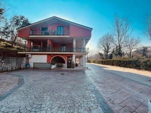 a red house with a balcony and a driveway at Pietrabianca Country House in Manocalzati