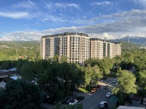 un gran edificio con coches estacionados en un estacionamiento en Апартаменты #3, en Almaty