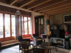 a living room with chairs and a tv and windows at Le Chai de Mario in Sadirac