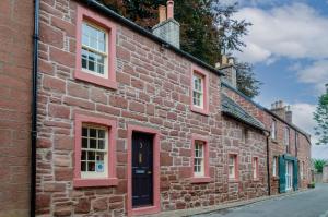 an old brick building with red windows on a street at Kirk Wynd Cottage in Kirriemuir