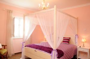 a bedroom with a canopy bed with a purple comforter at Corvos e Cadavais in Almodôvar