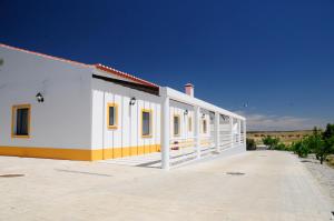 a white building with yellow windows and a blue sky at Corvos e Cadavais in Almodôvar
