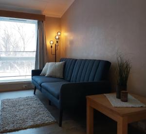 ein blaues Sofa im Wohnzimmer mit Fenster in der Unterkunft Varangertunet Rooms and Apartments in Jakobselv