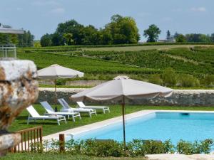 FronsacにあるMagnifique villa plain pied avec piscineのパラソル2つと椅子2脚付きのスイミングプール、スイミングプールを提供しています。